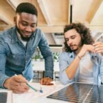 Two energy consultants from CalPacific Power in California reviewing solar panel plans during a solar consultation, emphasizing clean energy solutions.